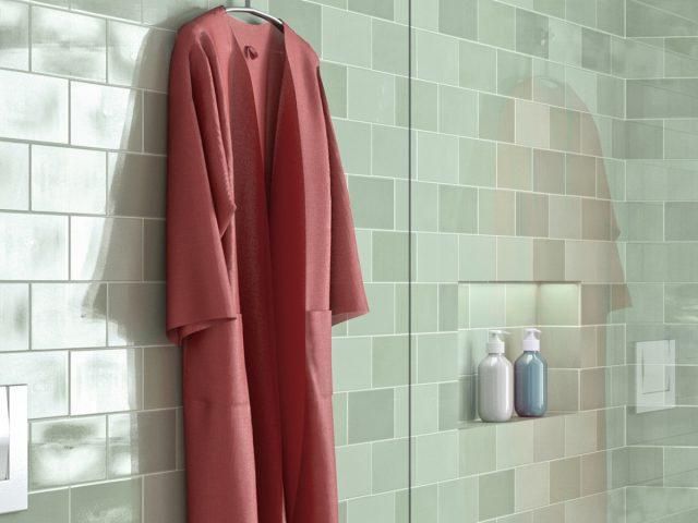 green tiled shower with red robe hanging on wall