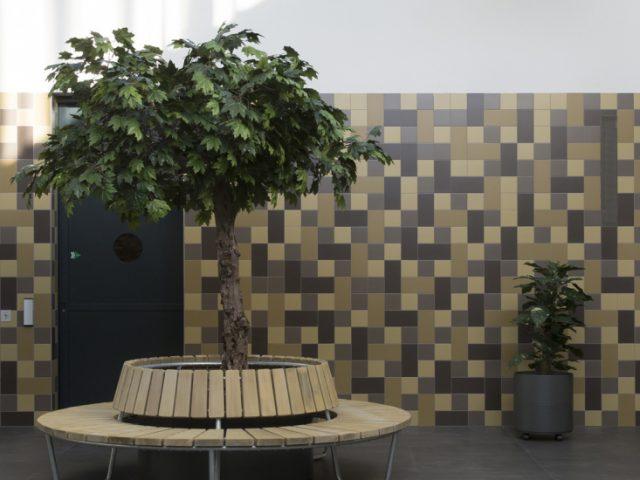 tan and brown tiled wall with bench and plants